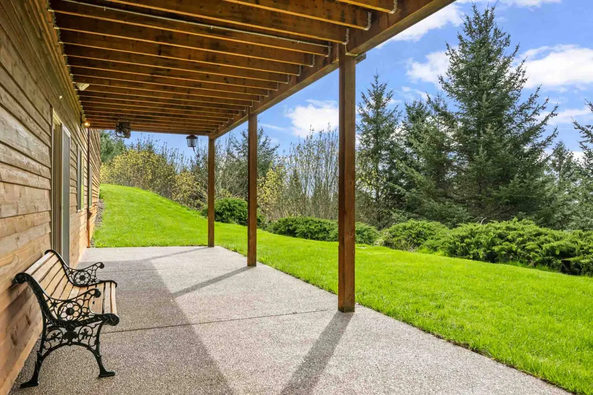 A tranquil exterior scene featuring a bench on a green lawn near a simple wooden structure, set against lush surroundings. The serene atmosphere invites relaxation and informal group conversations, ideal for downtime during a retreat.