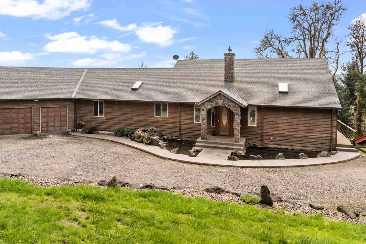 A welcoming exterior view of the home, featuring a distinctive wooden facade, arched front door, and a stone chimney. The landscaped pathway invites guests to explore and promises a warm arrival experience.