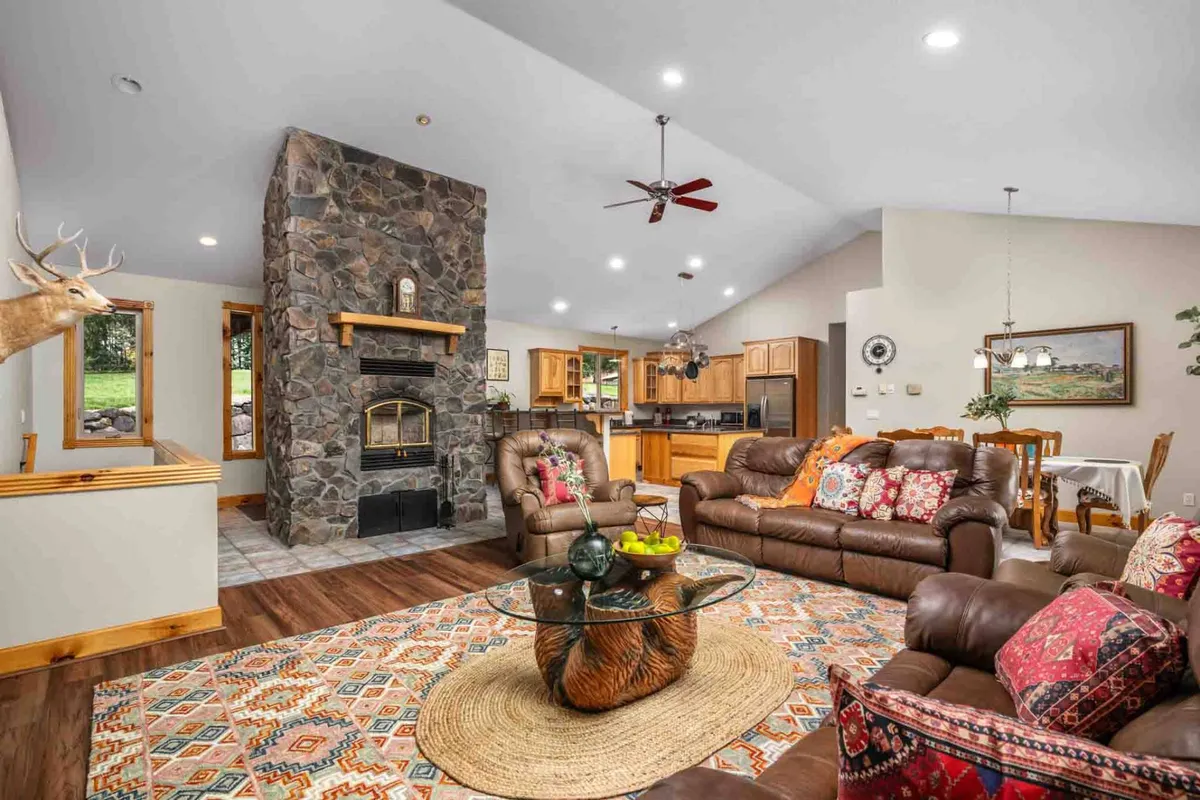 The image showcases a warm and inviting living room centered around a stunning stone fireplace. Plush seating, a stylish coffee table, and rich textile patterns create a cozy, welcoming atmosphere perfect for gathering with family and friends. The space exudes comfort and relaxation, ideal for intimate conversations, game nights, or unwinding by the fire after a day exploring Oregon wine country.