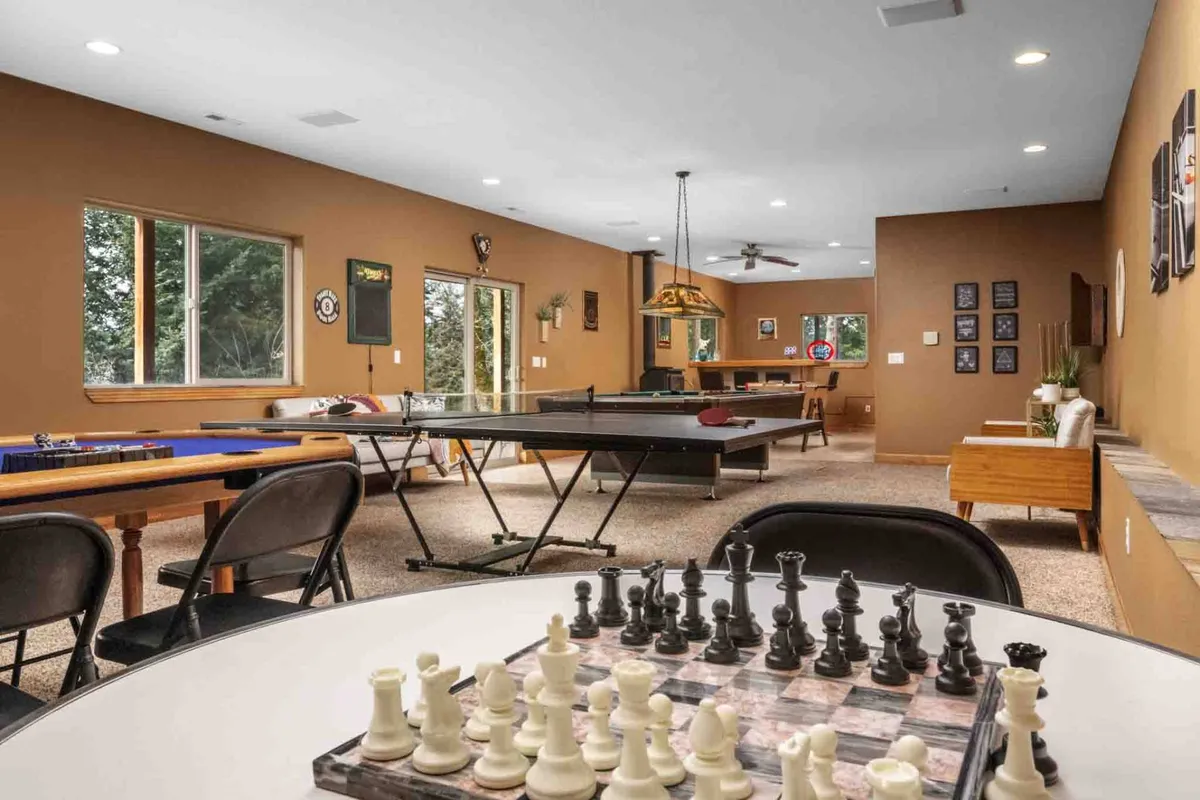A lively recreation space with a chess table, ping pong table, and an inviting bar area set near large windows. The natural light and open layout make it perfect for both intense matches and relaxed conversation over drinks.